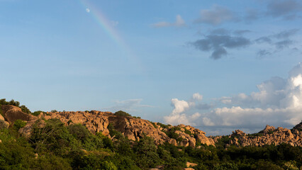 A dramatic view of Hampi's golden boulders with a rainbow just before the sunset.
