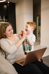 Kid make noise and disturb woman working talking on phone. Mom work on laptop from home with child. Homeschooling and freelance job. Quarantine and closed nursery school. Distance learning through war