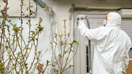 A masked worker in protective gear spray-paints urban surfaces for fresh renewal, echoing Global Handwashing Day and Eco-Friendly Living themes