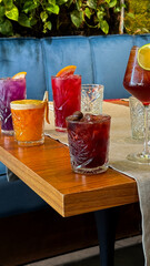 Colorful cocktail medley on rustic table, evoking National Cocktail Day vibes and summery Aperitivo Hour, vibrant refreshment oasis