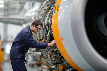Airplane mechanic performs maintenance on jet engine in hangar