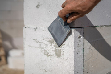 A worker expertly applies putty with a trowel to a wall at a construction site. This activity focuses on achieving a smooth finish before further stages of construction.