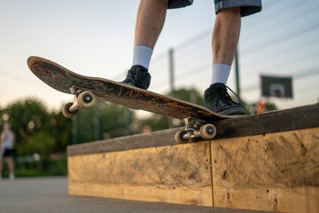 A skater is maintaining balance on a rail at a skate park during the late afternoon, showcasing skill and control while surrounded by a vibrant setting.