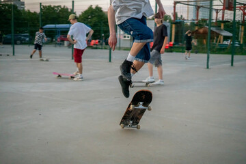Fototapeta premium A skateboarder executes a jump trick ollie, catching air above the ground at a skate park. The sun is setting, illuminating the background of eager onlookers.