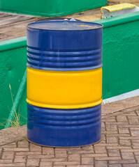 oil barrel in yellow and blue colors stands outside on the harbor quay
