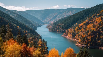 Picturesque autumn mountains and lake landscape with vibrant orange trees, calm water surface reflecting colorful foliage, azure sky, and tranquil nature scene perfect for outdoor travel and adventure
