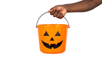 A hand holding an orange Halloween bucket with a carved pumpkin face