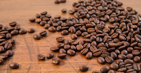 Scattered Coffee Beans on Wooden Table. Fresh Roasted Coffee. Morning Coffee Aroma.