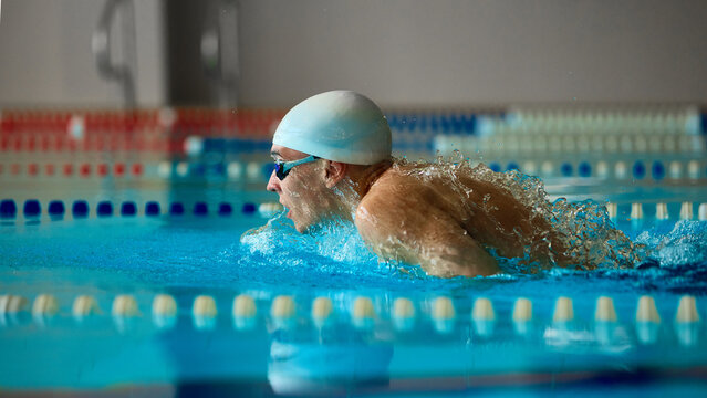 Swimmer executing butterfly stroke with intensity and water splash. Concept of sports advertising, swimming education, fitness and wellness, medical rehab, and inspirational athletic imagery.