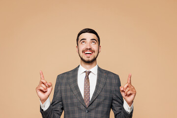Young successful employee business man corporate lawyer wear classic formal grey suit shirt tie work in office point index finger overhead on area isolated on plain beige background studio portrait.