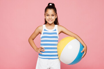 Traveler smiling happy kid child wear blue casual clothes near hotel pool hold inflatable rubber ball play game look camera isolated on plain pink background. Summer vacation sea rest sun tan concept.