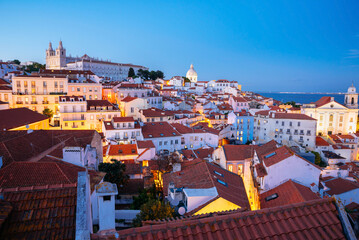 Panoramic Night View Over Alfama’s Rooftops and Tagus River from Miradouro da Graca Viewpoint in Lisbon, Portugal