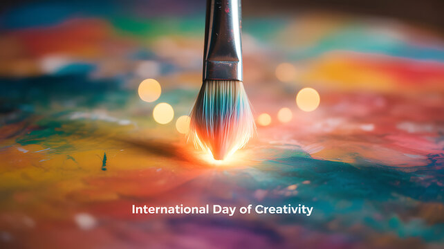 Paintbrush touching colorful canvas with glowing effect, celebrating International Day of Creativity