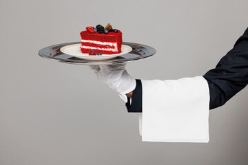 Close up cropped barista male waiter butler hold in hand tray with piece of cake dessert isolated on pastel plain grey color wall background studio. Restaurant concept. Copy space advertising mock up.