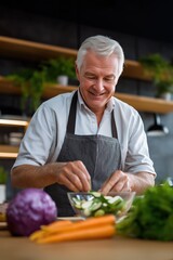 Elderly caucasian male preparing salad in modern kitchen setting