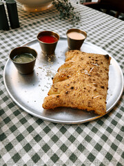 Delicious savory dish served on a metal plate with vibrant dipping sauces at a cozy eatery