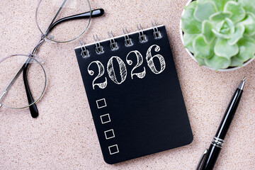 New year goals 2026. 2026 resolutions list with notebook, coffee cup, plant on table. Resolutions, plan, goals, action, checklist, idea concept. New Year 2026 resolutions, copy space