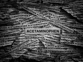 Strips of newspaper with the words Acetaminophen typed on them. Black and white. Close up.