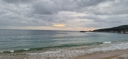Ocean, land, waves and cloudy sky