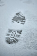 The footprints of the boots in the snow with a distinct pattern of the sole.
