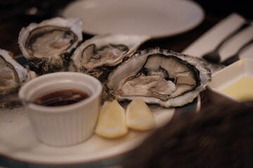 Fresh oysters with lemon and ice on wooden table, closeup stock photo