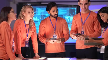 A data analytics team in a command center reviews a live security feed on a digital tablet. They are collaborating on a strategy to respond to a new threat on the network.
 - Powered by Adobe