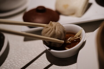 Chopsticks lifting a xiao long bao (steamed dumpling) served hot on a steaming tray xiaolongbao 小籠包