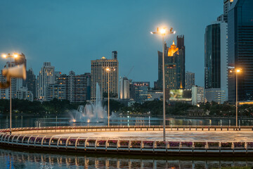 evening panorama of Bangkok city skyline with skyscrapers and Benchakitti park lake, vibrant cityscape view with reflections over pond water at dusk