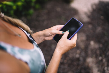 Close-up of woman’s hand using smartphone outdoors. Depicts tactile interaction with mobile technology in active and self-directed digital lifestyle.