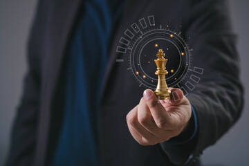 Close-up of businessman holding golden chess king piece with digital interface, symbolizing leadership, business strategy, decision making, innovation, and future-oriented corporate vision.