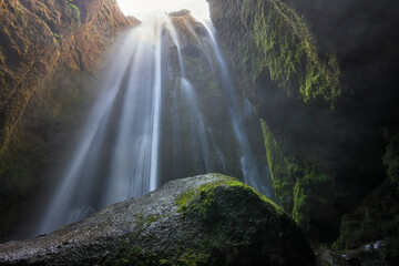 A waterfall falls inside a mountain cave in Iceland