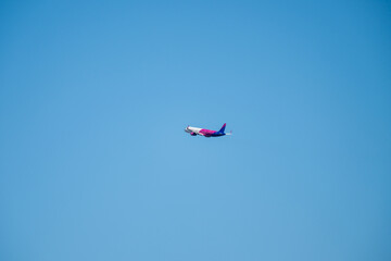 an airplane soars through a vast, cloudless blue sky in mid-flight.	
