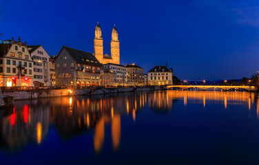Fototapeta premium Cityscape with classic buildings on Limmat River in Altstadt Old Town and iconic Grossmunster Romanesque cathedral, Zurich, Switzerland at sunset