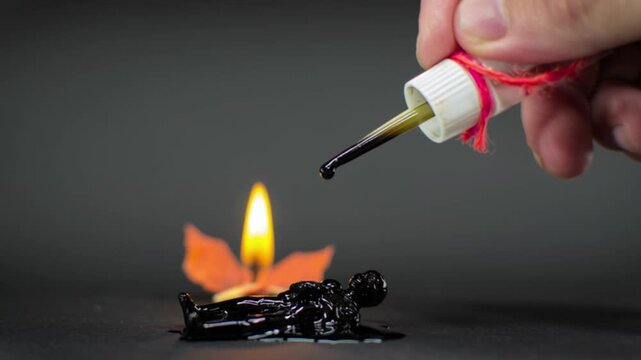 4K close-up of occultist dripping hot wax on voodoo doll with burning candle in background, representing dark magic ritual, black spell, mysticism, horror, and occult spiritual energy