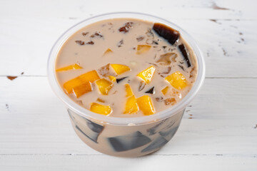 angle view bowl of milktea flavor syrup mixed with grass jelly and mangoes and peach gum and tapiocas and red beans and guiling jelly etc. at vertical composition