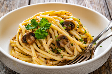 Pasta with champignons mushrooms in creamy sauce and parsley on wooden table	