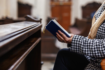 Christian woman is reading bible and praying in church. Silent prayer to God. Religion and spirituality concept