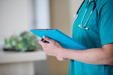 Portrait of adult man doctor stand with clipboard on the terrace
