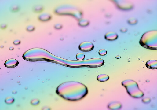 Close-up of iridescent water droplets on a colorful, reflective surface, creating a rainbow effect.
