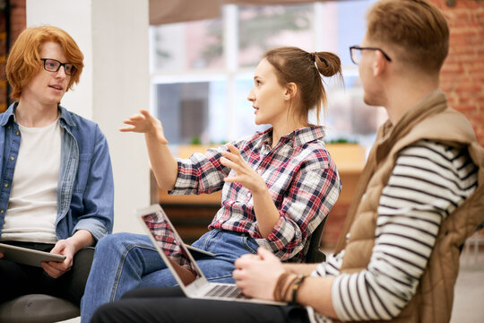 Expressing professional opinion. Young woman in casual wear sharing her business ideas with colleagues and gesticulating while having briefing in office