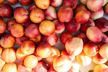 Peaches on farm market outdoors, fresh ripe fruits display for sale in sunlight, top view of organic seasonal fruits, natural healthy raw produce, vegetarian summer food, close-up top view