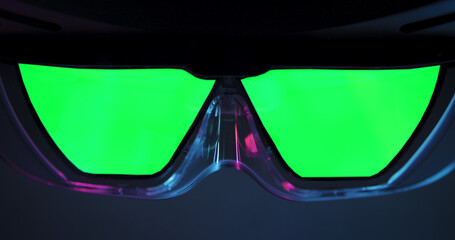Close up of futuristic virtual reality glasses with vivid green chroma key lenses, illuminated by neon reflections, perfect for technology themes, augmented reality concepts, or creative compositing p