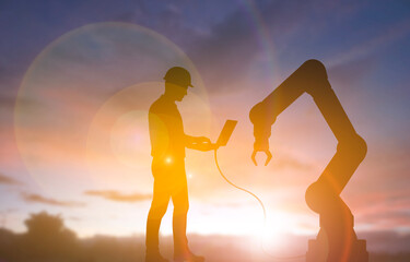 Engineer controlling industrial robot with laptop
