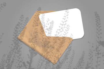 Natural lighting casts shadows from the field grass on an envelope with a sheet of white paper lying on a gray background. Mockup
