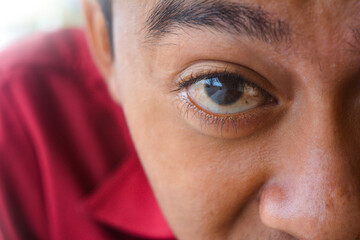Close-up of a human eye showing eyelashes, skin texture, and facial detail. The eye reflects light and creates a concept of focus, vision, observation, and human anatomy.