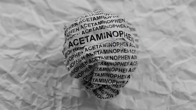 Crumpled paper ball with words Acetaminophen on a crumpled white paper background.