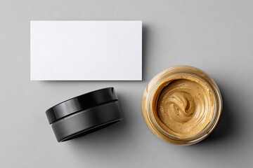 Flatlay mockup of a business card, a black jar, and a glass jar of a light brown cream