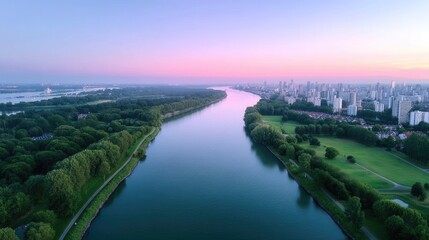 Fototapeta premium Scenic Aerial View of a City River at Dusk with Pink and Blue Sky Lush Green Trees and Distant Buildings in Golden Light