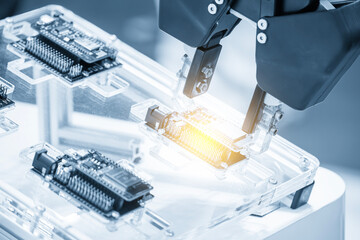 Close up scene the micro circuit board assembly process by robotic arm in the light blue scene.