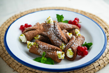 Sicilian cannoli filled with ricotta cheese cream and topped with chopped pistachios.